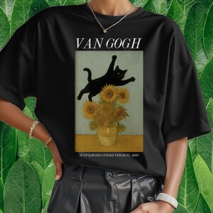 以下が含まれることがあります： 黒いTシャツ。ゴッホの「ひまわり」の絵画にインスパイアされたデザイン。ひまわりの花瓶の上を跳ねる黒猫が描かれており、上部に「VAN GOGH」、下部に「SUNFLOWERS (THIRD VERSION), 1888」の文字が配置されています。