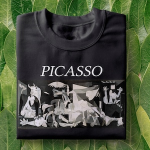 May include: Black t-shirt with a white print of a famous Picasso painting, "Guernica", and the word "PICASSO" above the image.