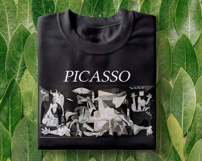 May include: Black t-shirt with a white print of a famous Picasso painting, "Guernica", and the word "PICASSO" above the image.
