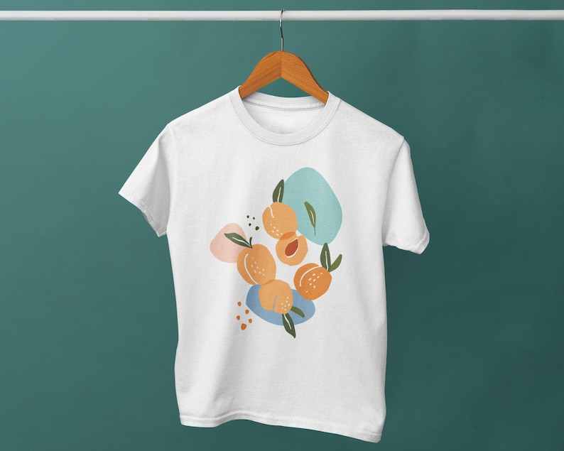 May include: White t-shirt with a graphic design of peaches and abstract shapes in shades of blue, orange, and pink.
