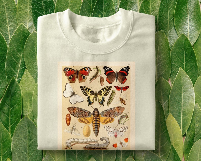 Op de afbeelding: Een wit T-shirt met een vintage illustratie van verschillende vlinders en motten. De illustratie bevat een verscheidenheid aan kleuren, waaronder rood, oranje, geel, zwart en wit.