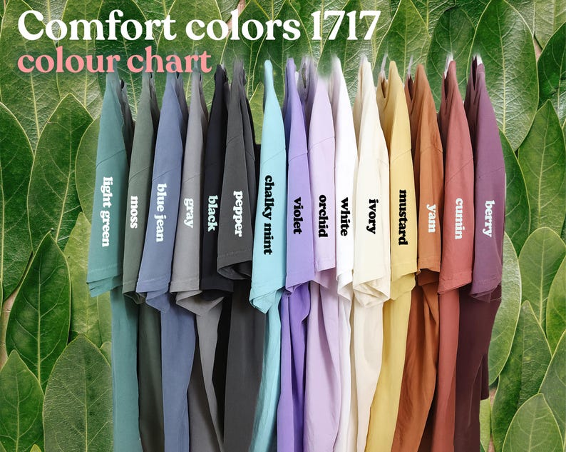 May include: A color chart of Comfort Colors 1717 t-shirts, showcasing a variety of hues. The shirts are displayed in a row, with colors including light green, moss, blue jean, gray, black, pepper, chalky mint, violet, orchid, white, ivory, mustard, yam, cumin, and berry.