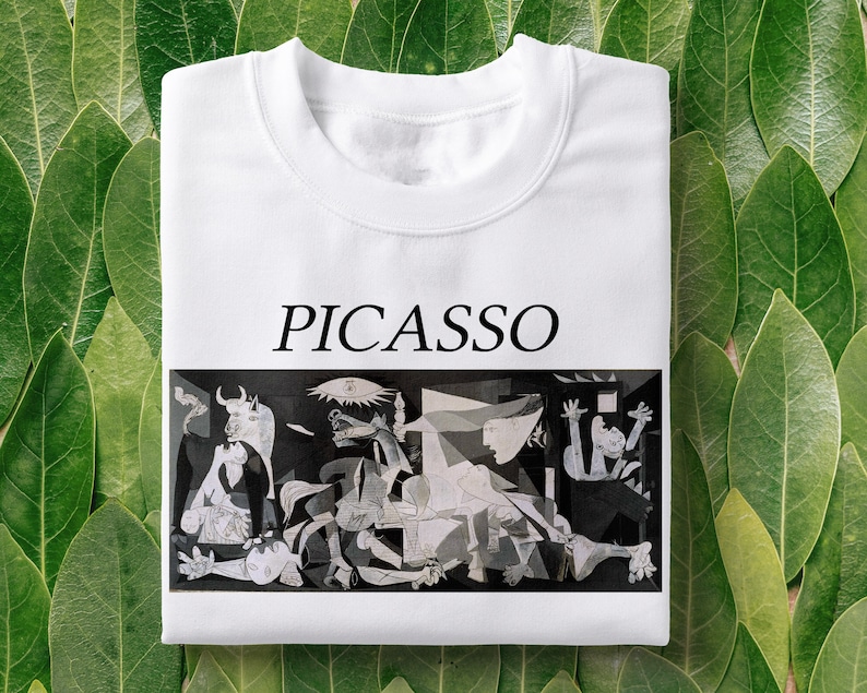 May include: White t-shirt with a black and white image of Picasso's Guernica painting and the word "PICASSO" printed in black above the image.