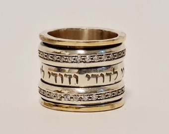 May include: A silver and gold ring with a Hebrew inscription and a row of small clear stones.