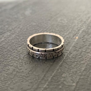 May include: A silver ring with Hebrew text inscribed around the band.