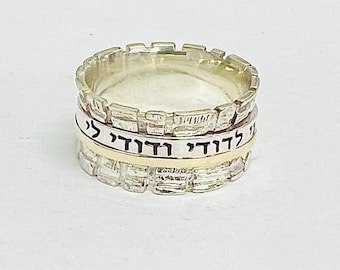 May include: A silver and gold spinning ring with the Hebrew words "L'dor V'dor" engraved on the band.