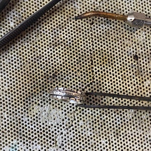 May include: A silver ring with Hebrew lettering on a metal workbench with tools.