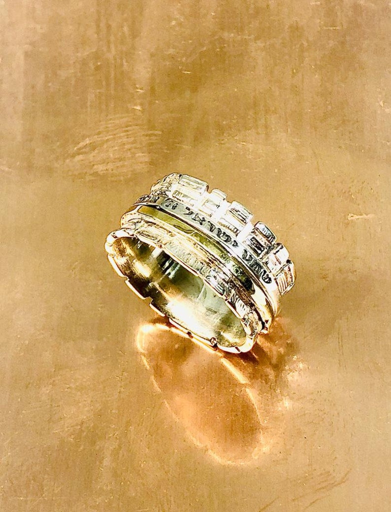 May include: A silver ring with a textured design, featuring multiple bands that appear to be stacked on top of each other.