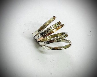 May include: A silver ring with multiple bands, some with a hammered texture, and one with a copper band.