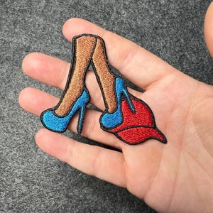 Puede incluir: Parche bordado para planchar con un par de tacones altos azules con piernas bronceadas y una gorra de béisbol roja.