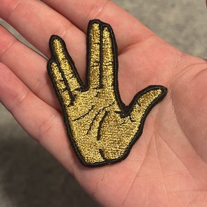 May include: Gold embroidered patch of the Vulcan salute hand gesture.