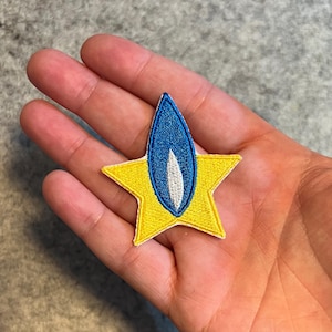 May include: A yellow star-shaped patch with a blue flame in the centre. The flame has a white outline.