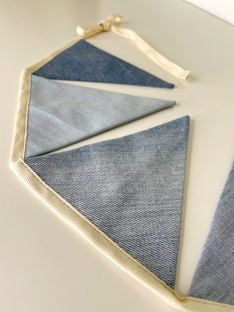 Handmade denim garland will be in various blue tones (from light blue to indigo denim), various textures but similar thicknesses (100% cotton or cotton mixed with spandex) and in various stages of wear.