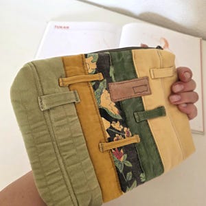 Repurposed denim zipper pouch made from waistbands and belt loops, featuring water-repellent lining. Unique floral detail adds a soft summer mood, ideal for slow living and eco-minded users.