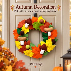 May include: A felt wreath featuring autumn-themed decorations including orange, yellow, red, and green leaves, brown and tan mushrooms, and small felt balls. The text reads Autumn Decoration, PDF pattern + sewing instructions and video, KNOPAtoys.