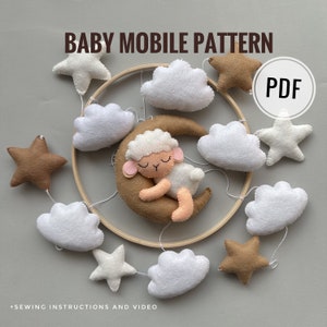 Könnte beinhalten: Ein DIY-Babymobil-Muster mit einem schlafenden Lamm auf einem Halbmond, Wolken und Sternen. Das Muster ist als PDF-Download erhältlich und beinhaltet Nähanleitungen und ein Video-Tutorial.