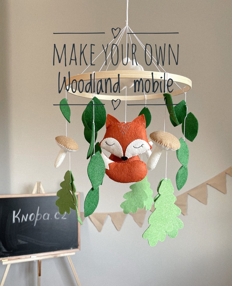 May include: A wooden mobile with a fox, leaves, mushrooms, and trees hanging from it. The mobile is labeled "Make your own Woodland mobile".