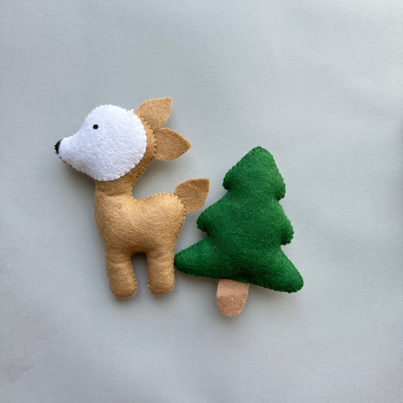 May include: A felt deer with a white face and a green felt Christmas tree. Both are handmade and would be a cute addition to a child's room.