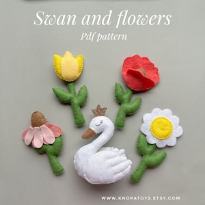 May include: Felt craft pattern for a white swan with a gold crown and four flowers: a yellow tulip, a red poppy, a pink flower, and a white daisy. The pattern is titled "Swan and flowers Pdf pattern".
