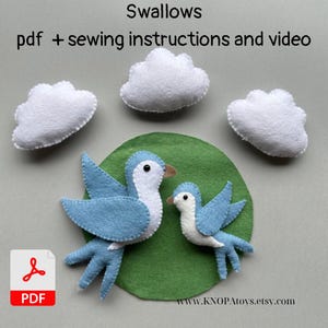 May include: A felt craft kit featuring two blue and white swallows, three white cloud shapes, and a green circular base. The image includes the text "Swallows pdf + sewing instructions and video" and a PDF icon.