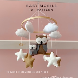 Könnte beinhalten: Ein DIY-Babymobil-Muster mit zwei braunen und grauen Eulen, weißen Wolken und goldenen und weißen Sternen. Das Muster enthält Näh-Anleitungen und ein Video.  "BABY MOBILE PDF PATTERN" und "www.KNOPAToys.etsy.com" sind auf dem Bild gedruckt.