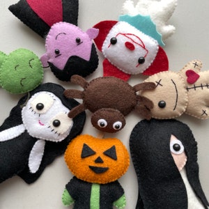 May include: A collection of felt Halloween characters, including a spider, a pumpkin, a vampire, a ghost, a voodoo doll, a ghoul, and a girl with long black hair.