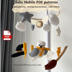 May include: A handmade baby mobile featuring felt shapes of a star, clouds, owl, lightning bolts, a witch's hat, and a broom. The mobile includes a gold-colored circle and is suspended from a wooden hoop. The text "Baby Mobile PDF patterns" is visible.