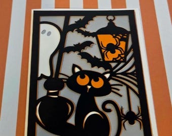 Puede incluir: Una tarjeta de felicitación rectangular con un diseño de papel recortado en capas. La silueta negra muestra un gato con ojos naranjas, un fantasma, murciélagos, una araña y una linterna colgante con un brillo naranja sobre un fondo gris claro.
