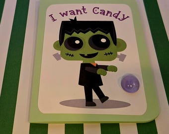 Puede incluir: Una tarjeta de felicitación rectangular de color verde claro con una ilustración de dibujos animados de un monstruo de Frankenstein verde con pelo negro, traje negro y puntos de sutura en las mejillas. El texto "I want Candy" está en morado.