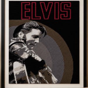May include: A framed needlepoint portrait of Elvis Presley in profile, rendered in shades of black, grey, and white. The word ELVIS is stitched in bold red letters at the top. The background features a circular design in muted brown and grey tones.