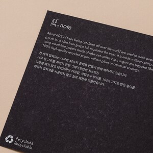 May include: A black and white image with the text "g.note" in white. The text explains that the paper is made from recycled materials, including coffee cups, sugarcane bagasse fibers, and recycled paper. The text also states that the paper is made without cutting down any trees. The image also includes a recycling symbol with the text "Recycled & Recyclable" in white.