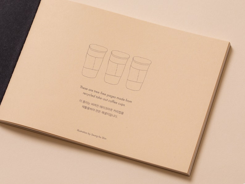 May include: Three line drawings of take-out coffee cups on a beige background. The text reads: "These are tree-free pages made from recycled take-out coffee cups. 이 종이는 버려진 테이크아웃 커피컵을 재활용하여 만든 재생지입니다. Illustration by Seung-ho Shin"