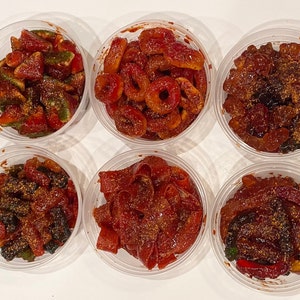 May include: Six clear plastic containers filled with different types of red gummy candies. The candies are covered in a red, sugary glaze and some have a sprinkle of red chili powder.