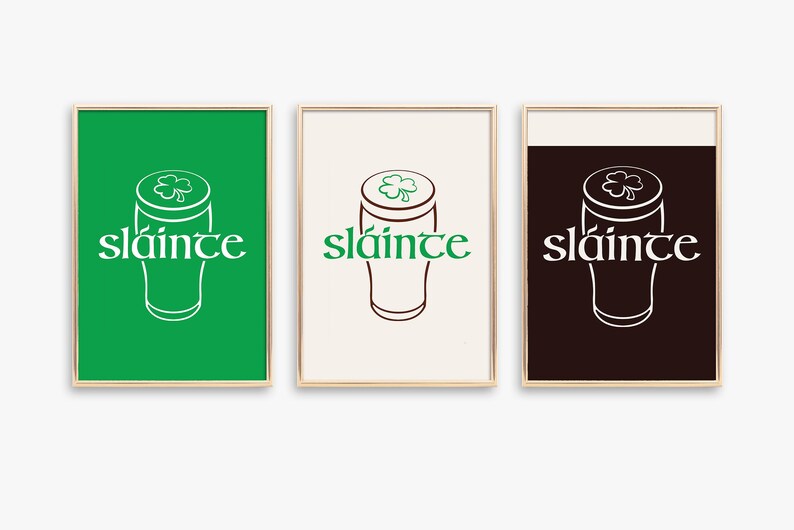 K&ouml;nnte beinhalten: Drei gerahmte Kunstdrucke mit goldenen R&auml;ndern. Jeder Druck zeigt ein stilisiertes Pintglas mit einem Kleeblatt und dem Wort "sl&aacute;inte" in einer dekorativen Schriftart. Die Hintergr&uuml;nde sind gr&uuml;n, cremefarben und dunkelbraun.