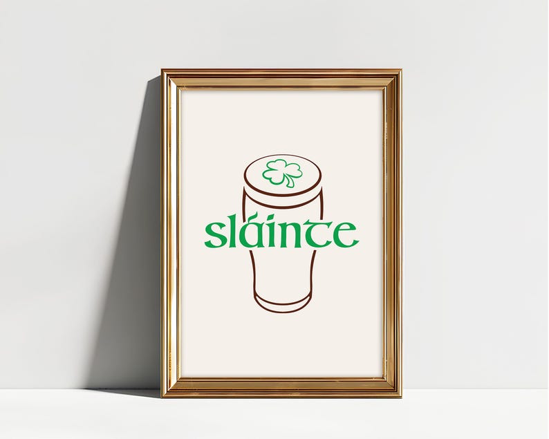 K&ouml;nnte beinhalten: Gerahmter Druck mit goldenem Rahmen. Der Druck zeigt eine braune Umrisszeichnung eines Bierkrugs, gekr&ouml;nt von einem gr&uuml;nen Kleeblatt. Das Wort "sl&aacute;inte" steht in gr&uuml;ner Schrift darunter.
