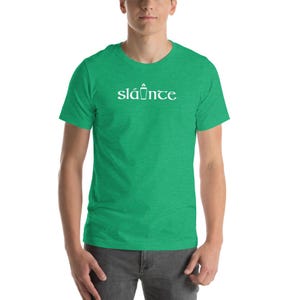Puede incluir: Una camiseta verde con la palabra "sl&aacute;inte" impresa en blanco. La palabra est&aacute; escrita en una fuente estilizada. La camiseta es de manga corta y cuello redondo. "Sl&aacute;inte" es una palabra ga&eacute;lica.