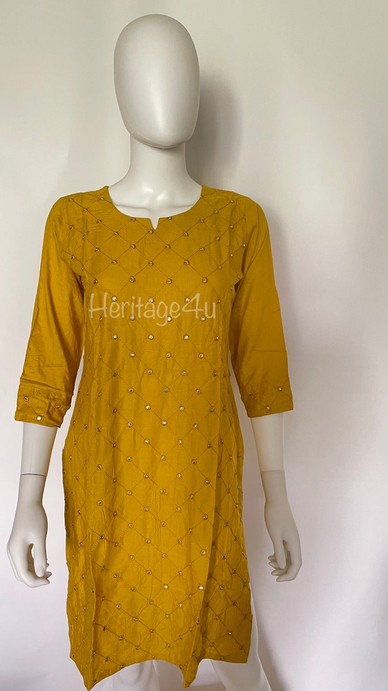 May include: A mustard yellow kurta with a diamond pattern and gold embellishments. The kurta has a round neckline and three-quarter sleeves.