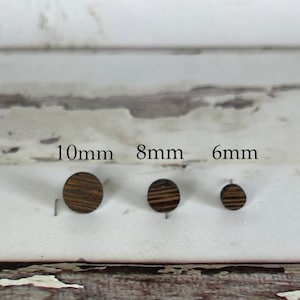 May include: Three wooden round earrings in different sizes: 10mm, 8mm, and 6mm. The earrings are dark brown with a wood grain pattern.