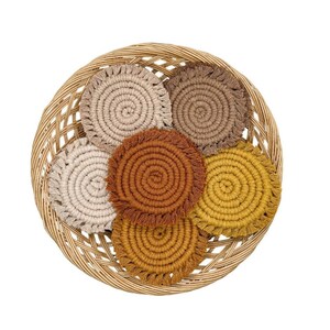 May include: Six round crocheted coasters in a wicker basket. The coasters are in shades of brown, beige, and yellow with fringe edges.