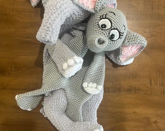 May include: Two handmade gray crochet elephant stuffed animals. The larger elephant has pink inner ears and white accents on its feet. The smaller elephant is nestled on top of the larger one. The elephants have embroidered eyes and trunks.