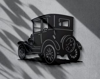 May include: Black metal wall art of a vintage car. The classic automobile features a detailed design of the body, wheels, and other components. The car is mounted on a textured grey wall, with shadows from foliage.