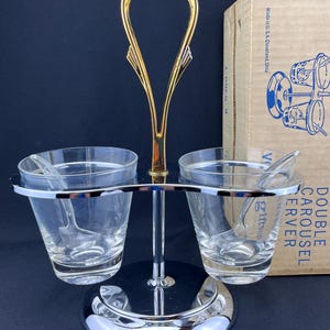 May include: A chrome double carousel server with two glass condiment dishes and spoons. The server has a gold handle and a round base. The box says "Double Carousel Server" and "Made in U.S.A. Cleveland, Ohio."