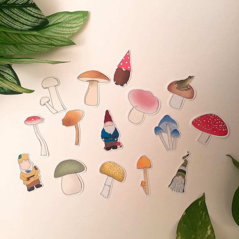 Puede incluir: Un conjunto de 13 pegatinas de setas y gnomos de colores. Las pegatinas presentan varios dise&ntilde;os de setas, incluyendo setas rojas y blancas con lunares, setas marrones con lunares blancos y setas azules con lunares blancos. Tambi&eacute;n hay dos pegatinas de gnomos, una con un gorro rojo y otra con un gorro azul.