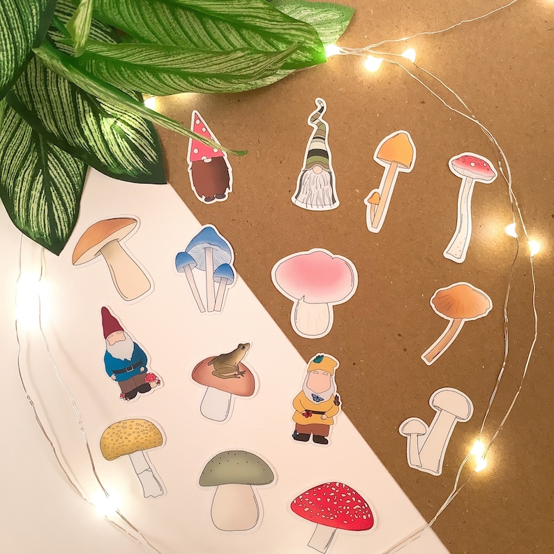 Puede incluir: Un conjunto de 14 pegatinas de setas y gnomos de colores. Las pegatinas presentan varios dise&ntilde;os de setas, incluyendo setas con lunares rojos y blancos, setas marrones y setas blancas con lunares rojos. Tambi&eacute;n hay dos pegatinas de gnomos, una con un gorro rojo y otra con un gorro azul.