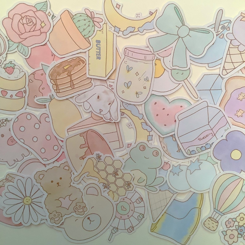 May include: A collection of pastel-colored stickers featuring various cute designs, including a watermelon, a frog, a bunny, a bear, a jar of fireflies, a slice of cake, a pot of cactus, a crescent moon, a heart, a honeycomb, a pair of boots, a hot air balloon, and a blueberry carton. The stickers are perfect for adding a touch of whimsy to journals, planners, laptops, and other items.