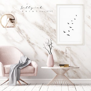 Peut inclure: Une impression minimaliste en noir et blanc d'un vol d'oiseaux en formation. L'impression est encadr&eacute;e et accroch&eacute;e &agrave; un mur en marbre blanc. L'impression est dans un salon avec un fauteuil rose, une table basse en m&eacute;tal dor&eacute; et un vase avec une branche s&egrave;che.