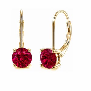 Puede incluir: Un par de pendientes de oro con cierre de palanca, cada uno con una piedra preciosa roja oscura de corte redondo sujeta por cuatro garras. El metal tiene un acabado en oro amarillo pulido y el cierre de palanca asegura los pendientes.