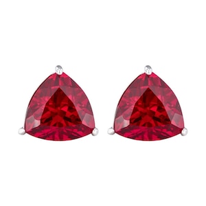 May include: A pair of stud earrings featuring trillion-cut, deep red gemstones set in silver-toned metal. Each earring has a triangular shape with faceted surfaces that reflect light, secured by a small metal prong at each of the three corners.