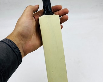 May include: A miniature wooden cricket bat with a black rubber handle, resting on a wooden base.