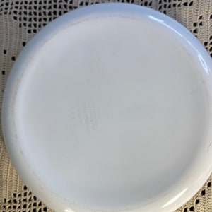 Puede incluir: Plato para hornear de cer&aacute;mica blanca con forma redondeada y un solo asa. El fondo del plato tiene una peque&ntilde;a inscripci&oacute;n descolorida.